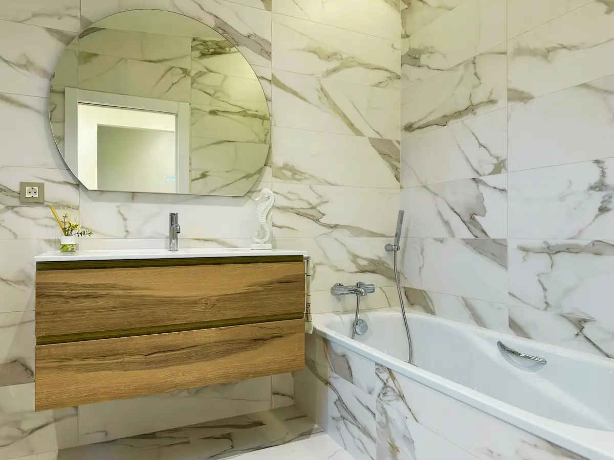 Baño con bañera encastrada y revestimiento de mármol en Urbanización La Solana