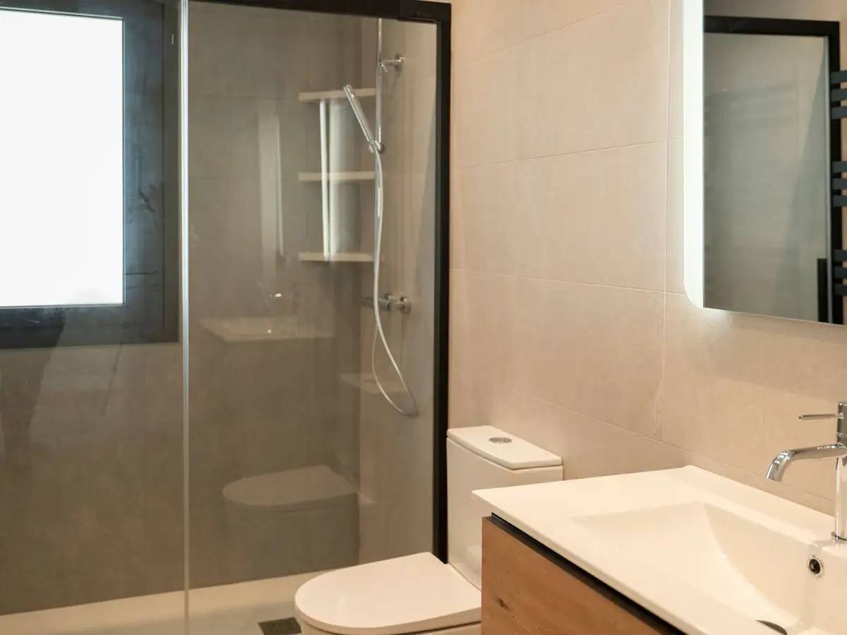 Baño con ducha de cristal y mueble de madera en vivienda unifamiliar Forfontía