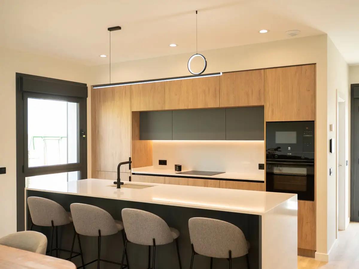 Cocina con isla blanca e iluminación led en vivienda unifamiliar Forfontía