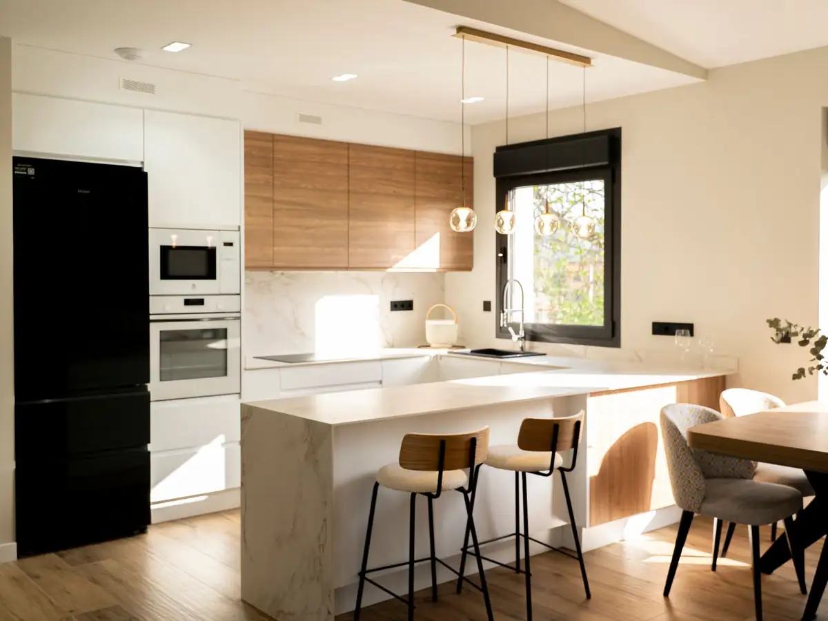Cocina con isla de mármol y muebles de madera en vivienda unifamiliar Forfontía