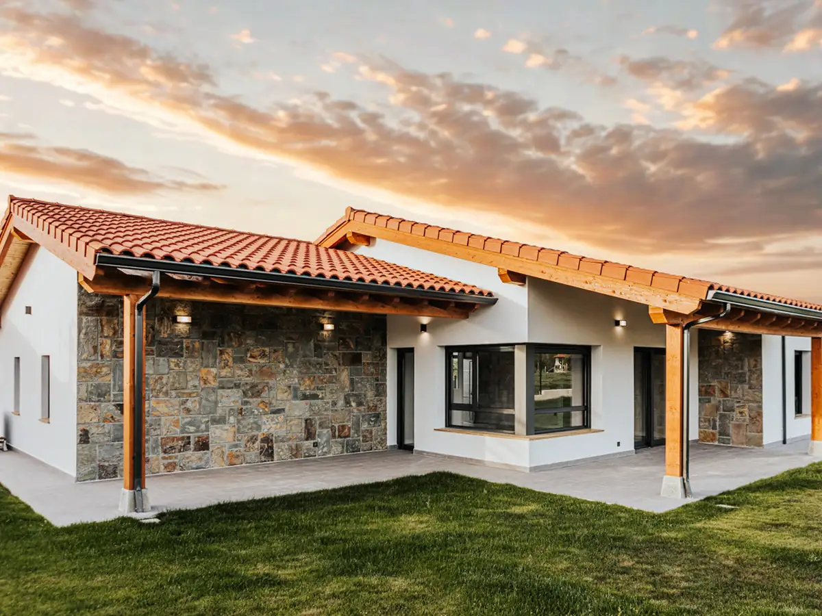 Fachada de piedra natural con estructura de madera al atardecer en Urbanización La Solana