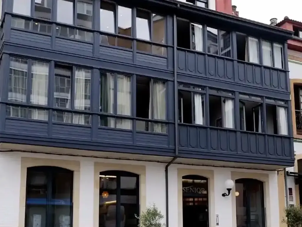 Fachada del edificio Senior Suits con galerías acristaladas en Pola de Siero