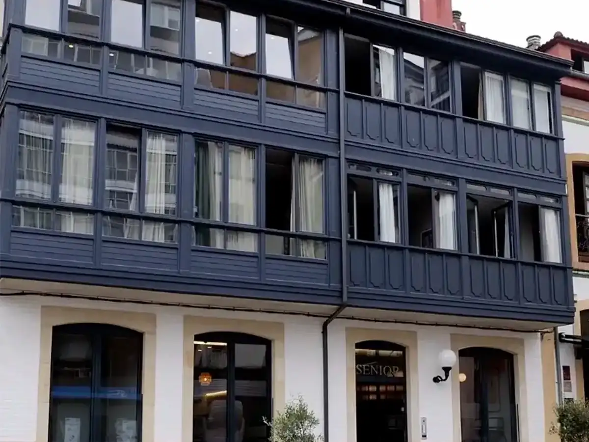 Fachada del edificio Senior Suits con galerías acristaladas en Pola de Siero